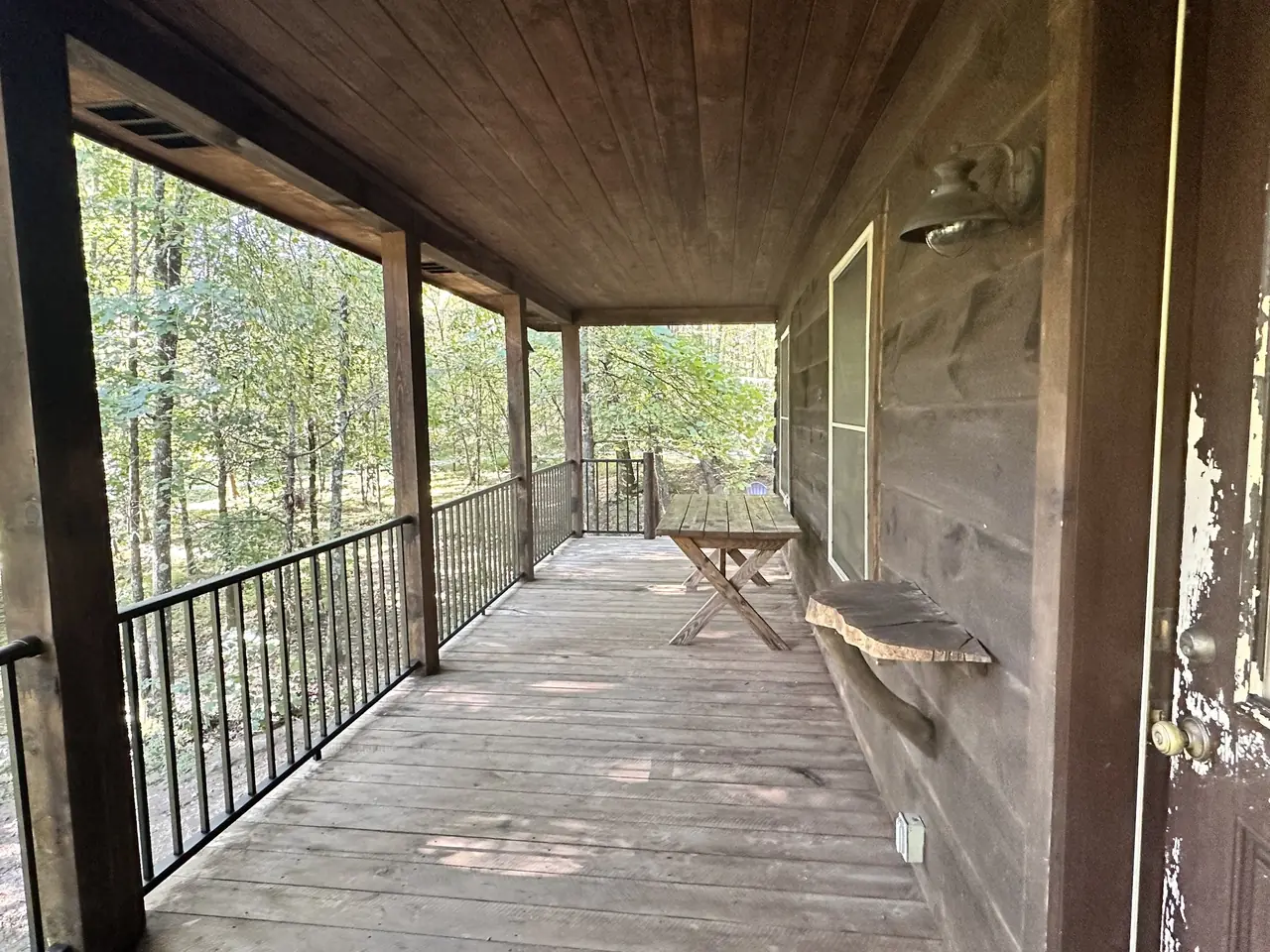 Covered porch with a bench looking into the woods