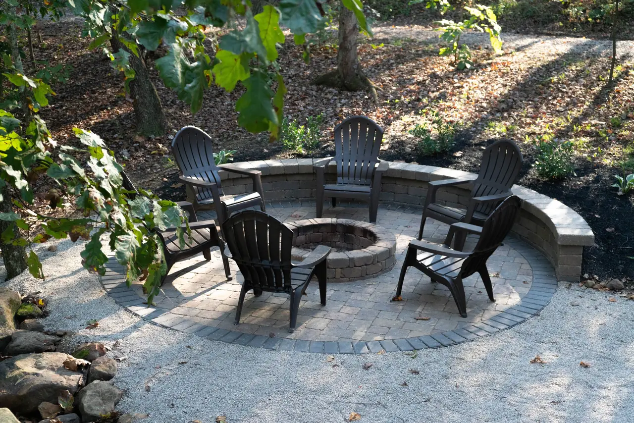 Stone fire pit ringed by Adirondack chairs